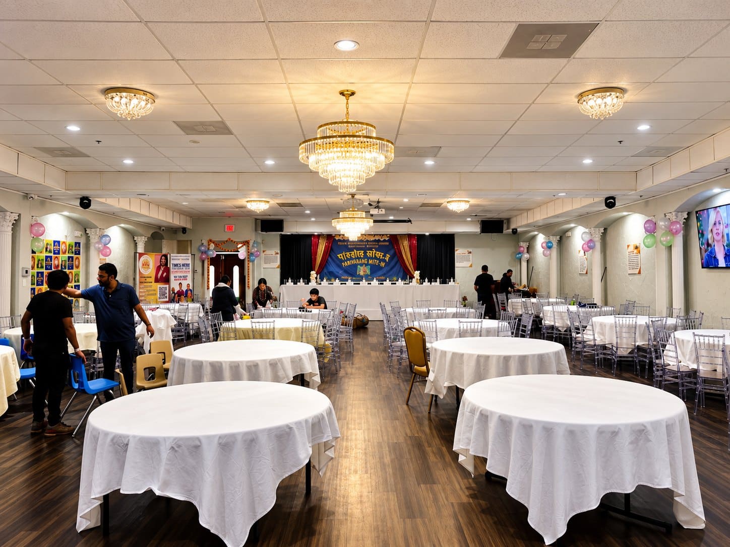 The banquet hall set with white linens and chandeliers
